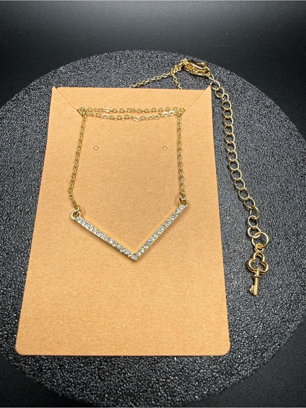 Gold V-Shaped Crystal Pendant Necklace with key charm in the back.